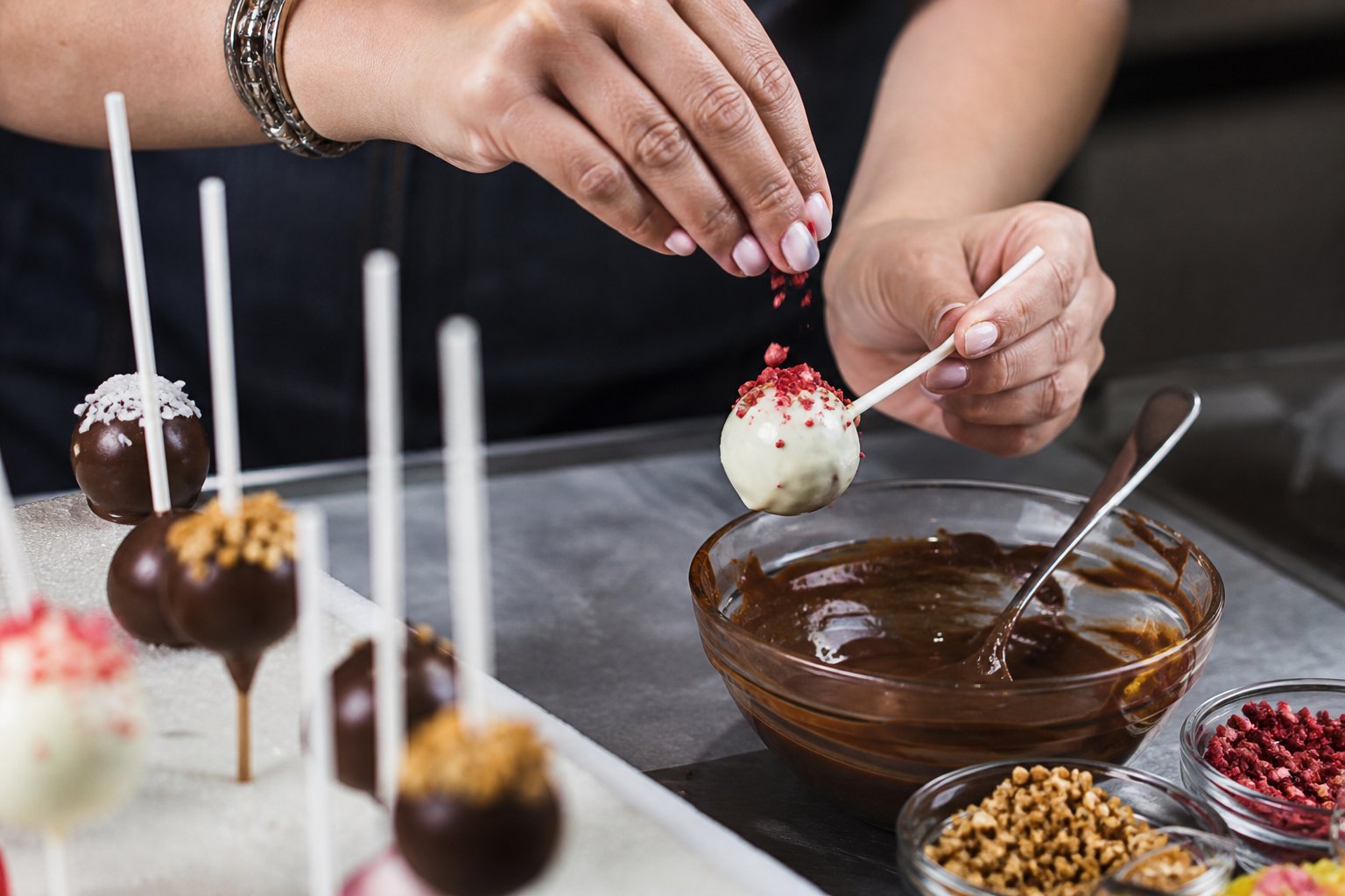 Pastelero decorando cake pops artesanales con chocolate y toppings de colores
