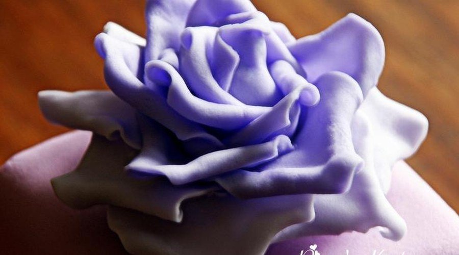 Pastelero dando los últimos detalles a una tarta fondant personalizada con rosas rosas